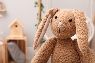 Photo of Cute toy rabbit in room, closeup. Space for text