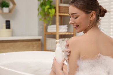 Photo of Woman taking bath with shower gel in bathroom, space for text