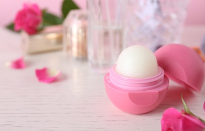 Lip balm and flowers on white wooden table, closeup