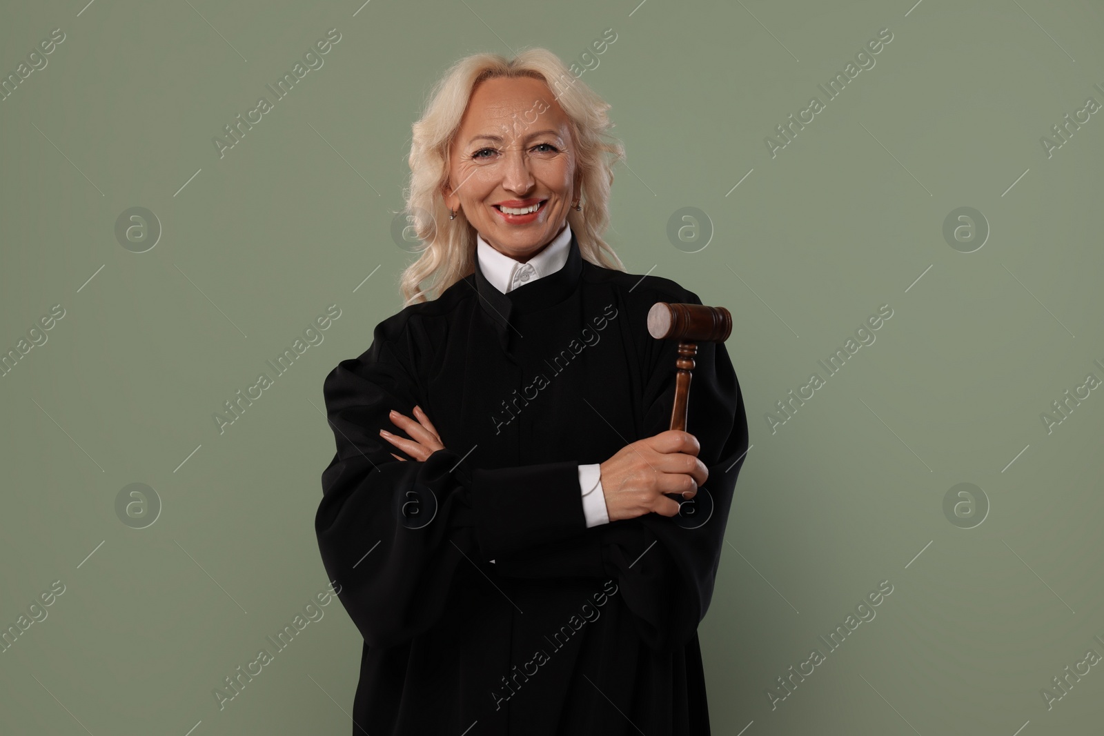 Photo of Smiling senior judge with gavel on green background
