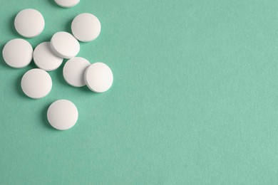 Pile of white pills on green background, flat lay. Space for text