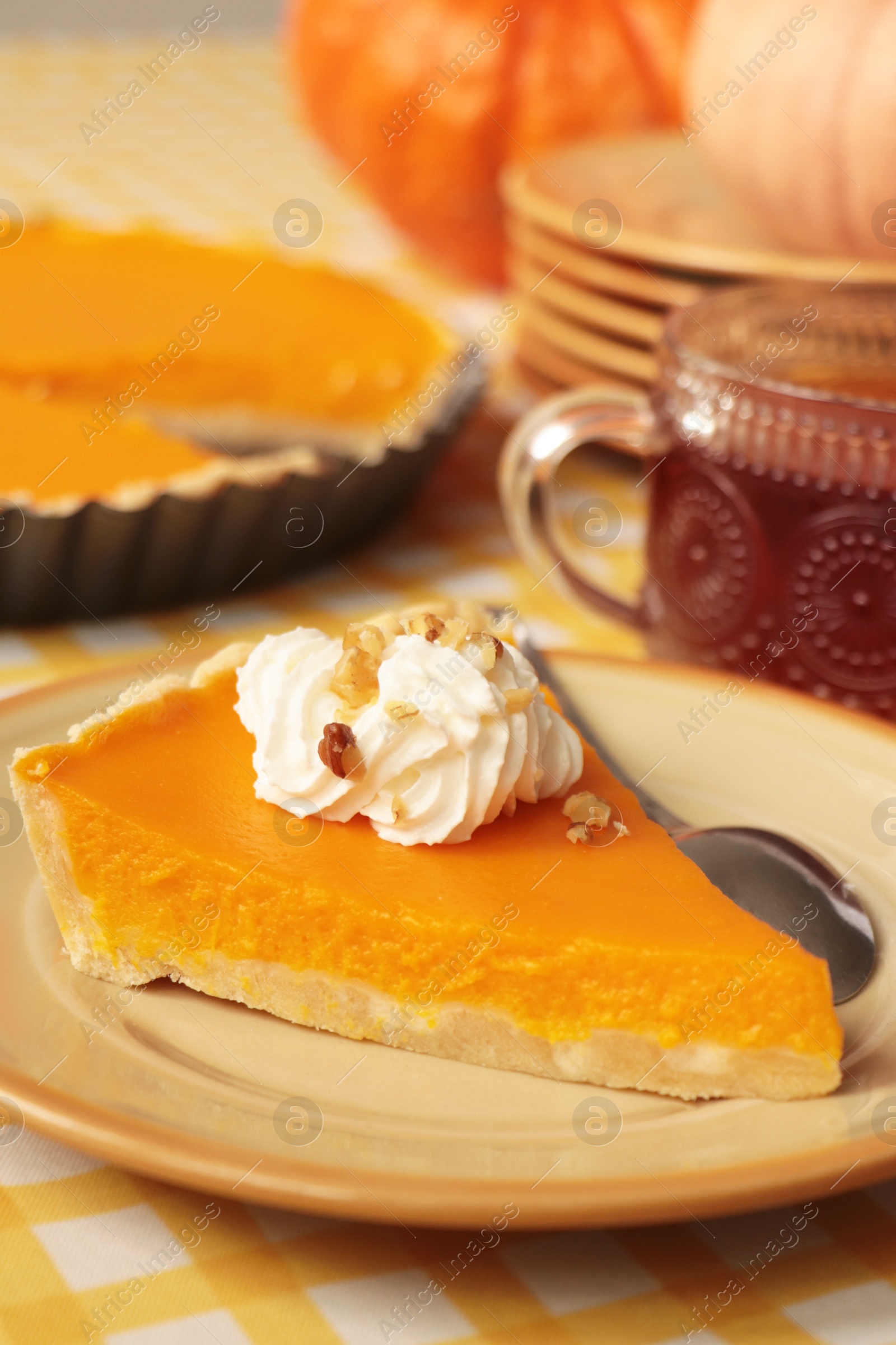 Photo of Piece of fresh homemade pumpkin pie served with whipped cream and tea on table, closeup