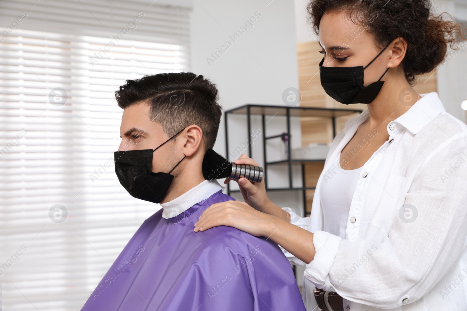 Photo of Professional stylist working with client in salon. Hairdressing services during Coronavirus quarantine