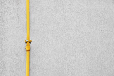 Yellow gas pipe near beige wall outdoors, space for text