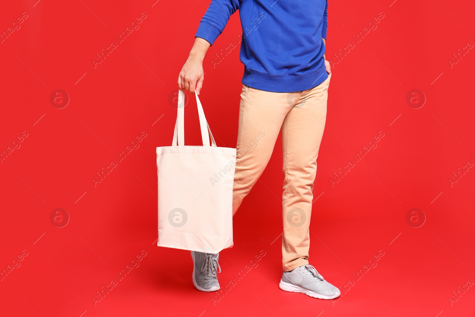 Photo of Young man with eco bag on red background, closeup