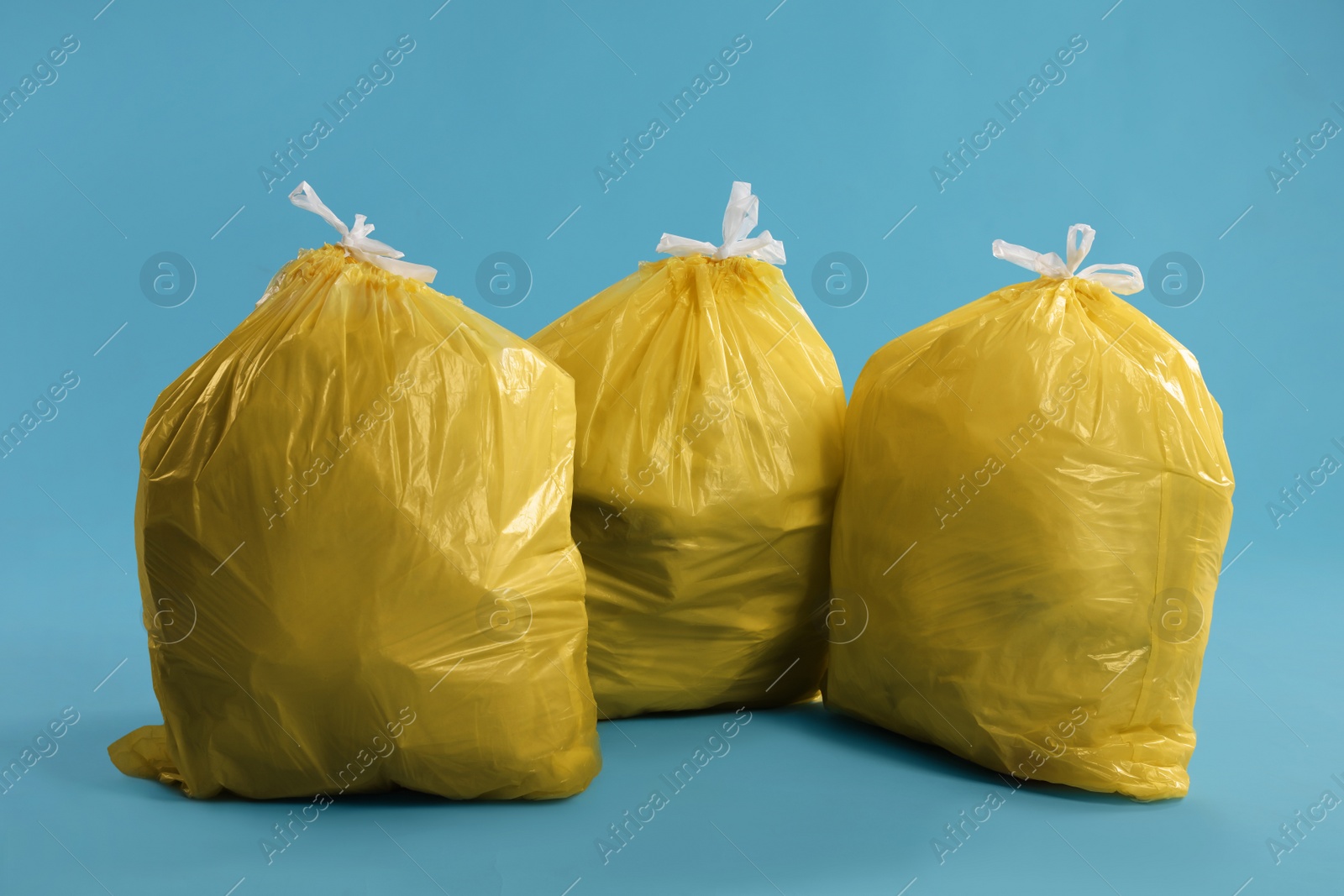 Photo of Trash bags full of garbage on light blue background