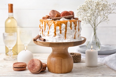 Delicious homemade cake with caramel sauce and cookies on table