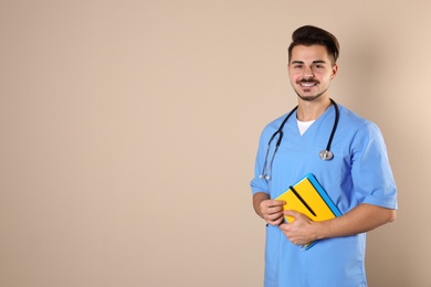 Young medical student with notebooks on color background. Space for text