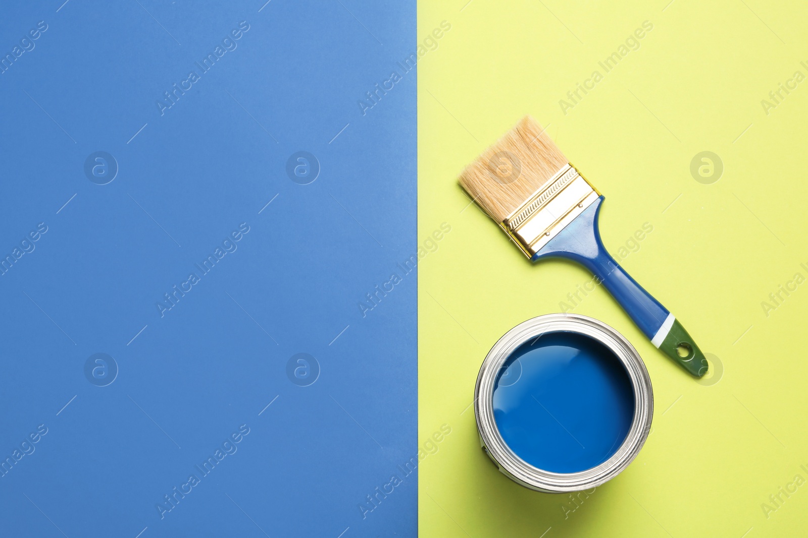 Photo of Open paint can, brush and space for text on color background, top view