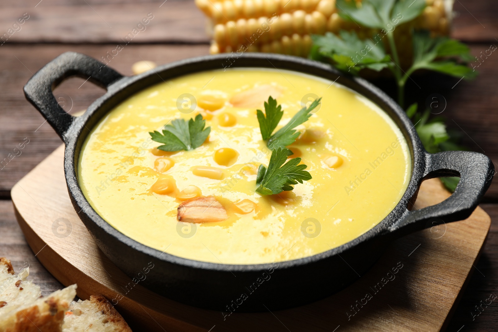 Photo of Delicious creamy corn soup on wooden table, closeup