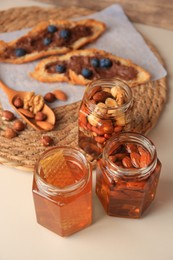 Photo of Jars with nuts and honey on beige table
