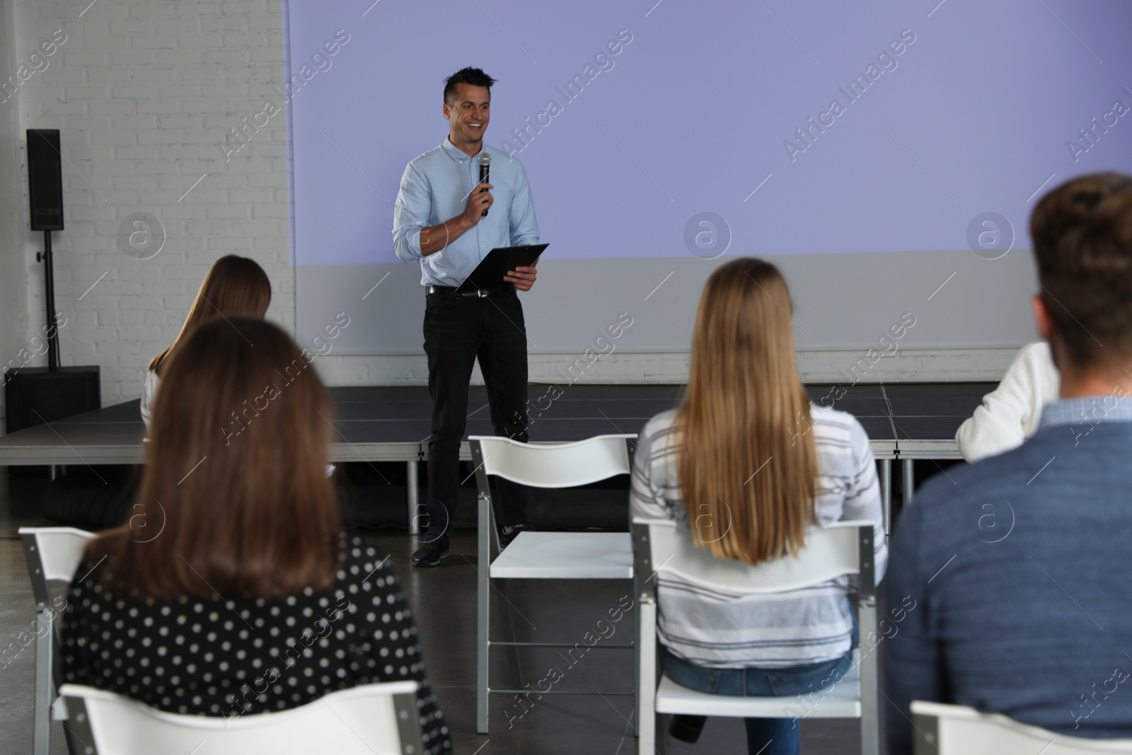 Photo of Male business trainer giving lecture in conference room with projection screen