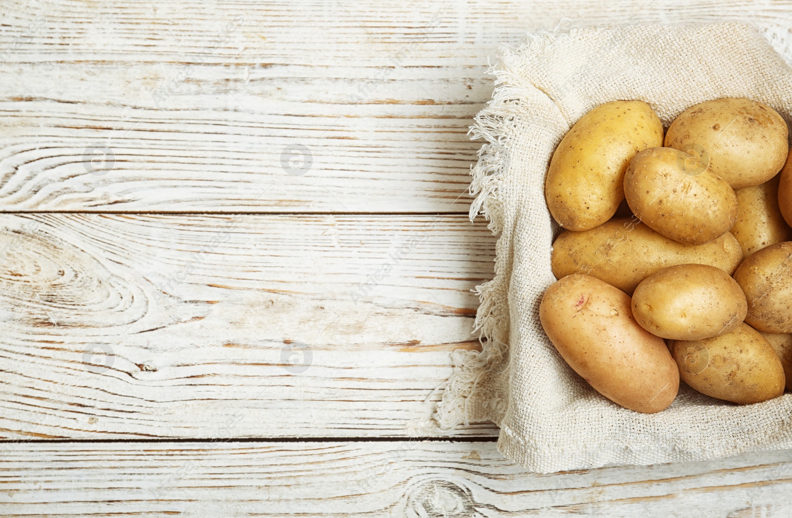 Photo of Fresh ripe organic potatoes on wooden background, top view