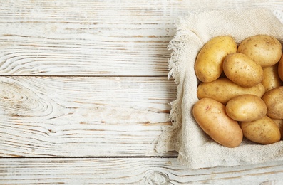 Fresh ripe organic potatoes on wooden background, top view