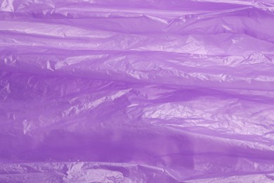 Photo of Crumpled purple plastic bag as background, top view