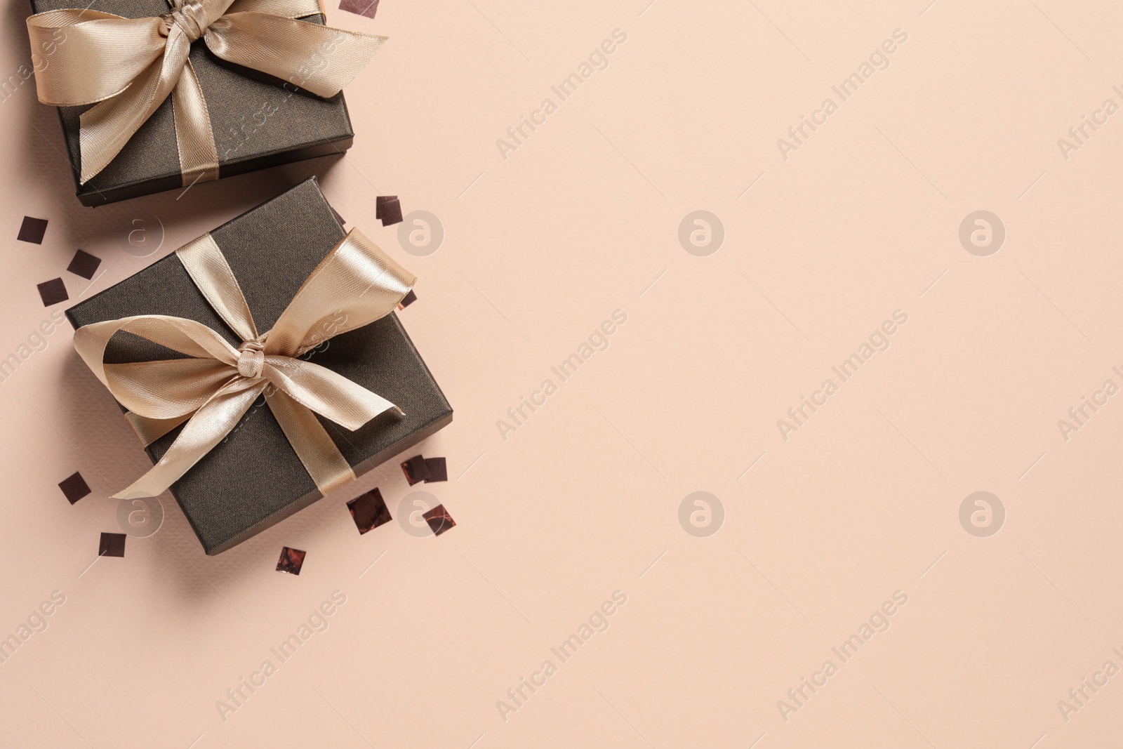 Photo of Beautiful gift boxes and confetti on beige background, flat lay. Space for text