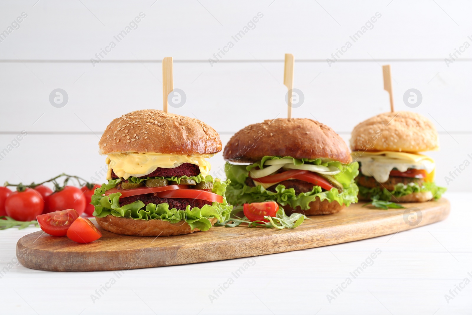 Photo of Delicious vegetarian burgers served on white wooden table