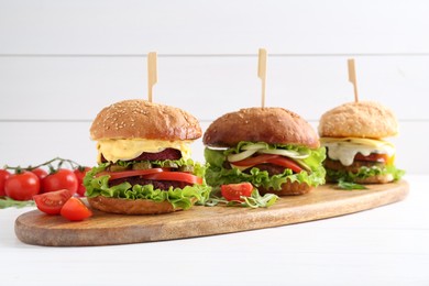 Photo of Delicious vegetarian burgers served on white wooden table