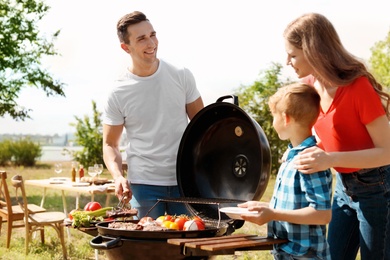 Photo of Happy family having barbecue with modern grill outdoors