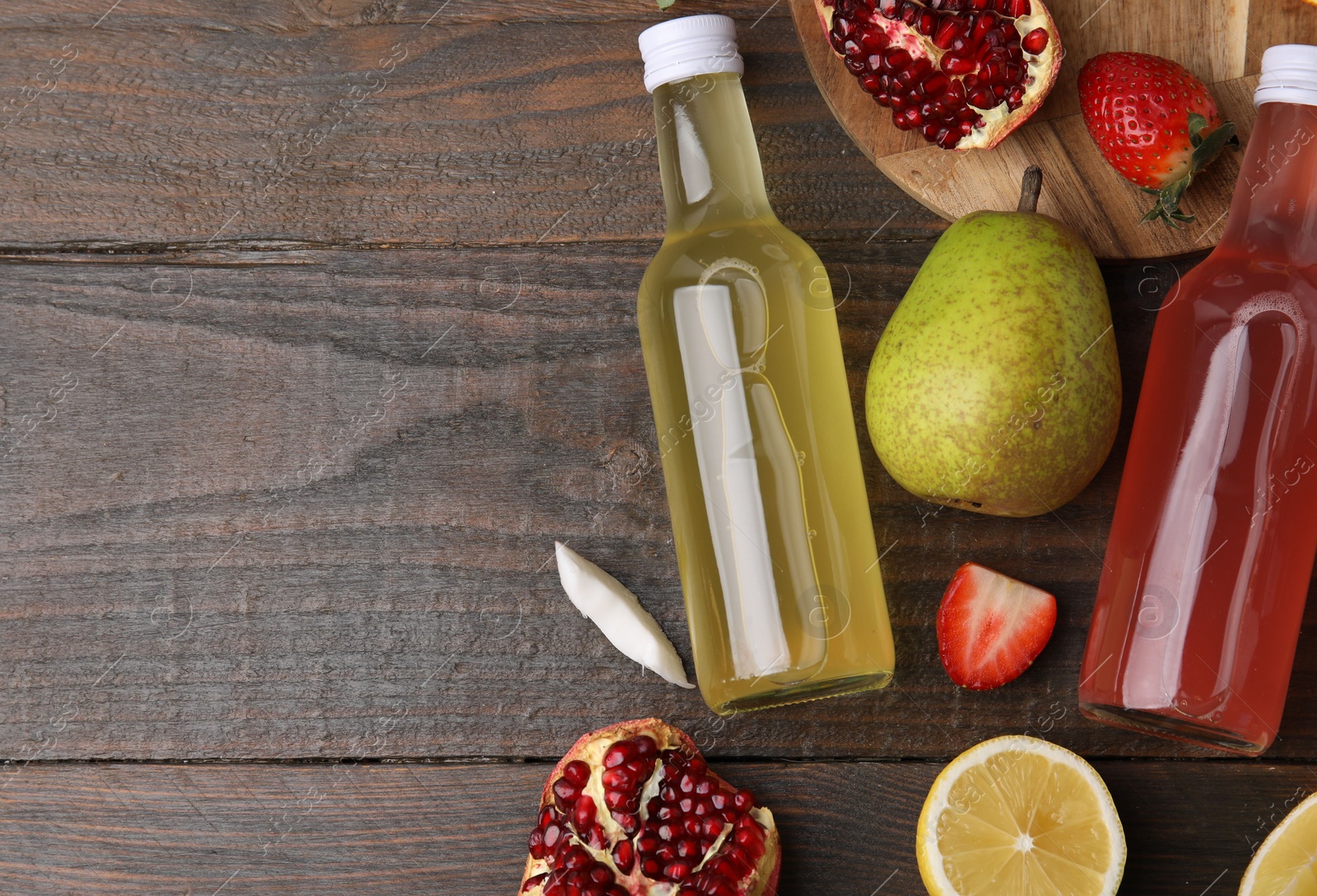 Photo of Delicious kombucha in glass bottles and fresh fruits on wooden table, flat lay. Space for text