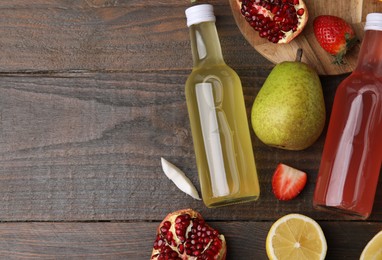 Photo of Delicious kombucha in glass bottles and fresh fruits on wooden table, flat lay. Space for text