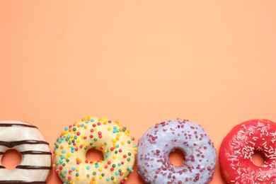 Delicious glazed donuts on orange background, flat lay. Space for text