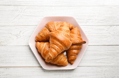 Photo of Plate with tasty croissants on white wooden background, top view. French pastry