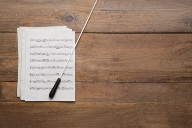 Photo of Conductor's baton and sheet music on wooden table, flat lay. Space for text