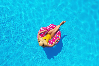 Young woman with inflatable ring in swimming pool, top view