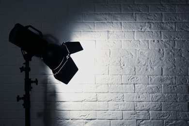 Photo of Professional photo studio lighting equipment near brick wall. Space for text