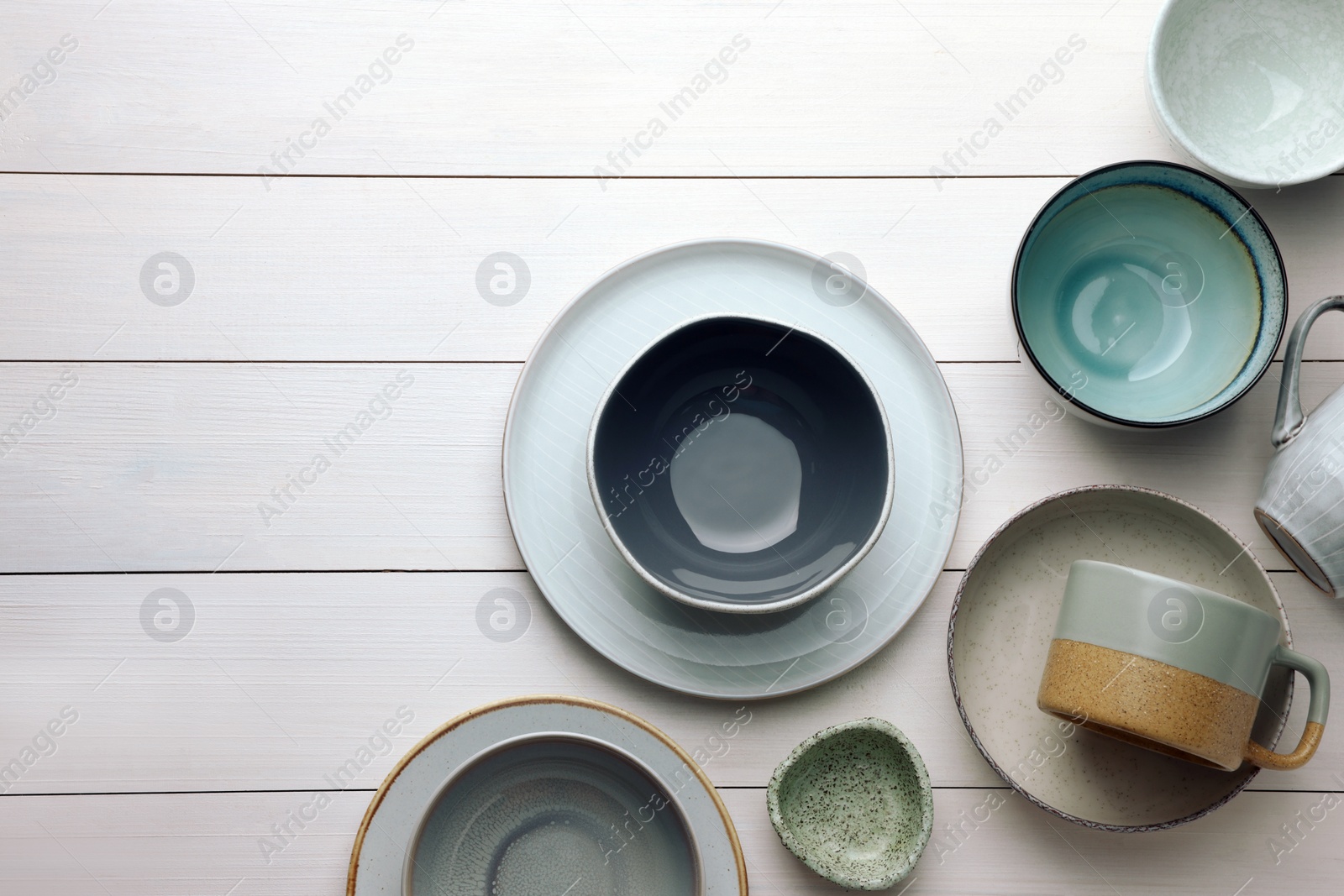 Photo of Stylish empty dishware on white wooden table, flat lay. Space for text