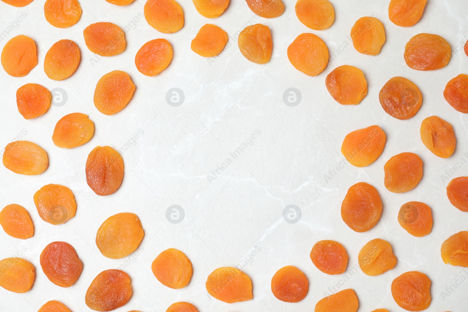 Photo of Frame made of apricots on light background, top view with space for text. Dried fruit as healthy food