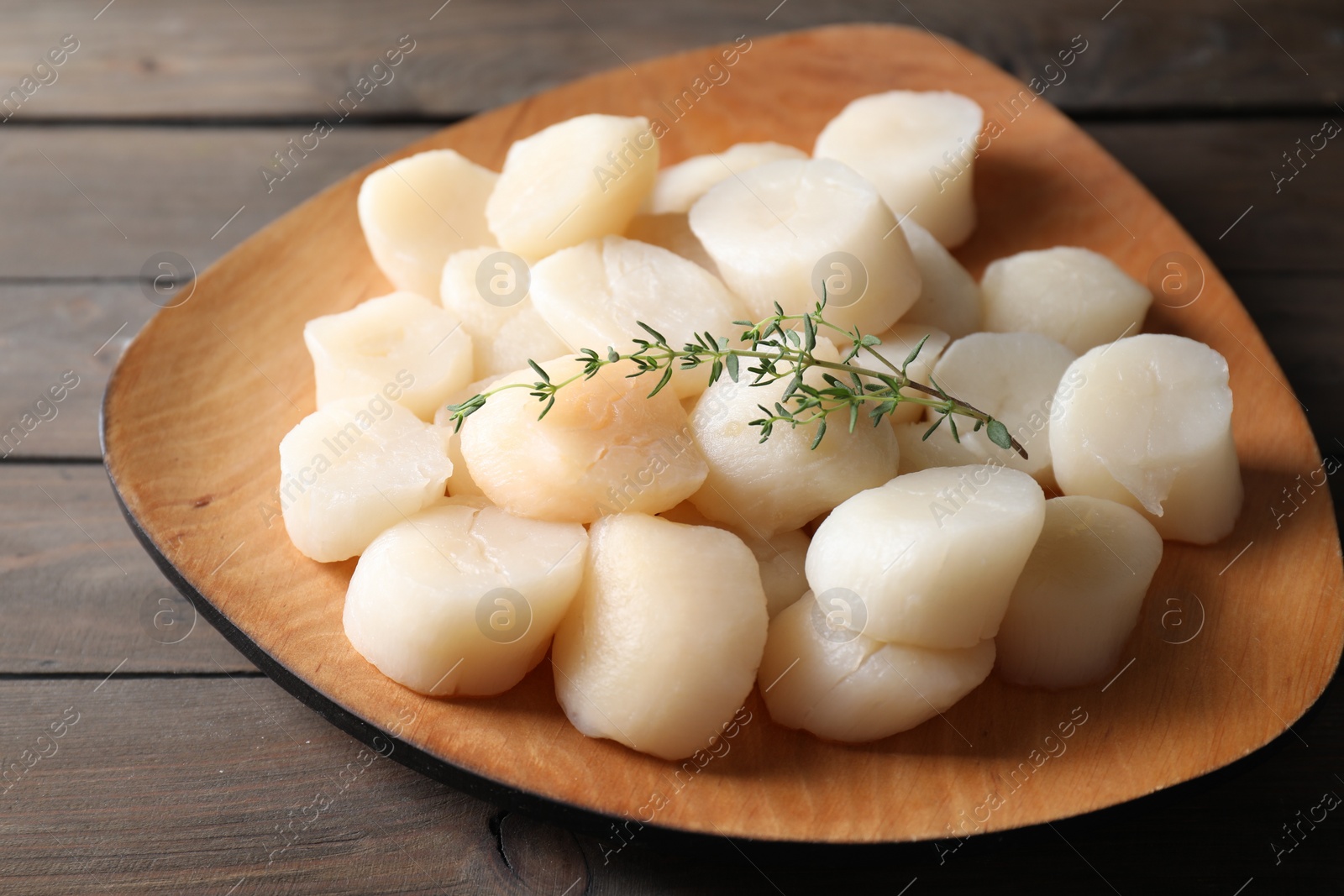 Photo of Fresh raw scallops and thyme on wooden table, closeup