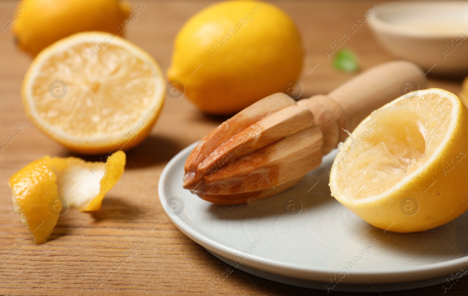 Photo of Plate with wooden juicer and lemon half on table. Refreshing drink recipe