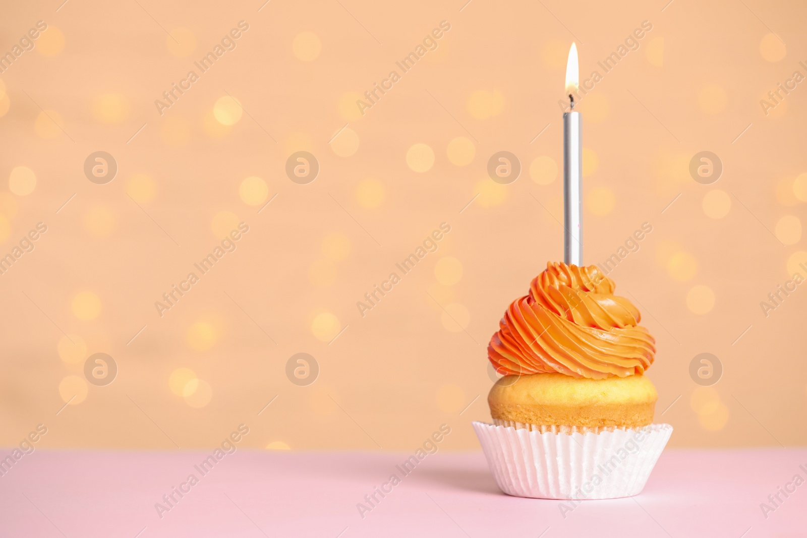 Photo of Birthday cupcake with candle on table against festive lights, space for text