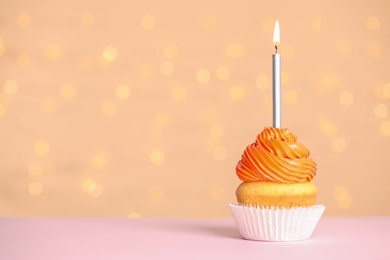 Birthday cupcake with candle on table against festive lights, space for text