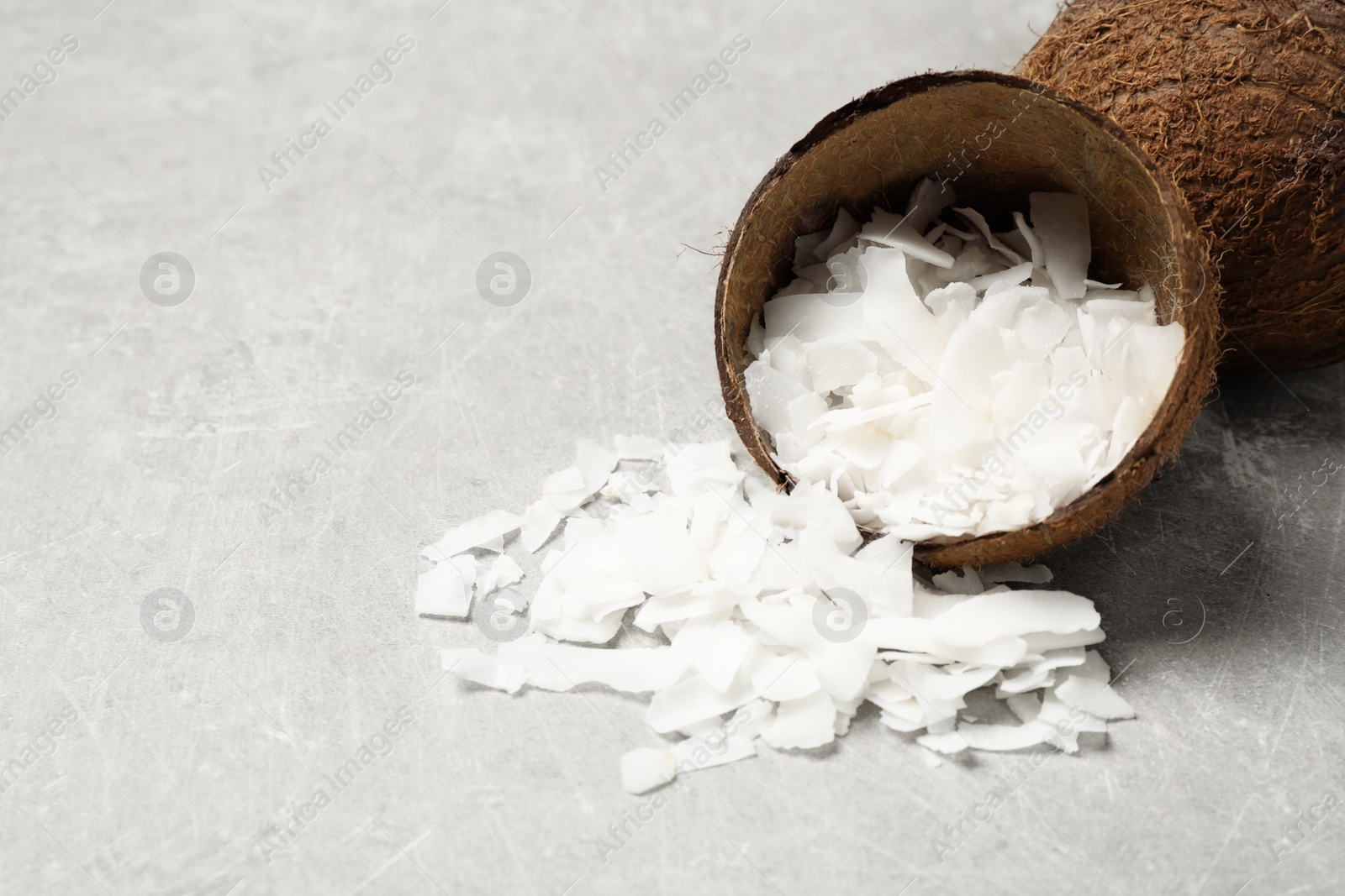 Photo of Tasty coconut chips and shell on grey table