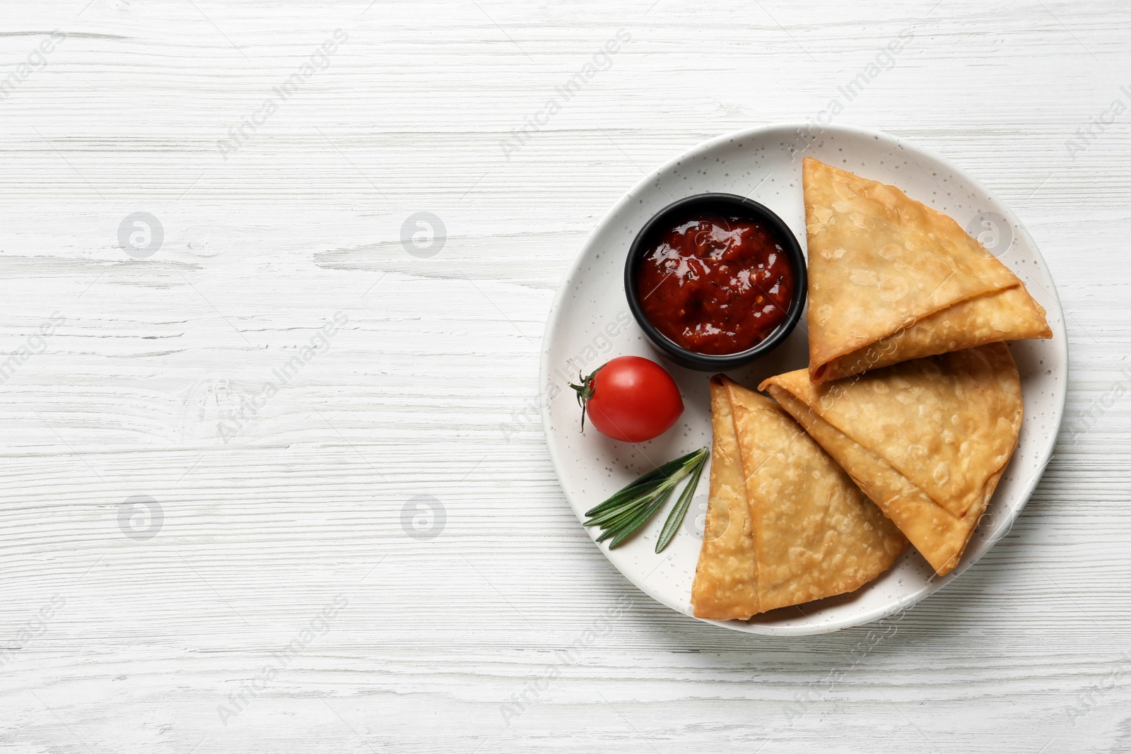 Photo of Fresh delicious crispy samosas served on white wooden table, top view. Space for text