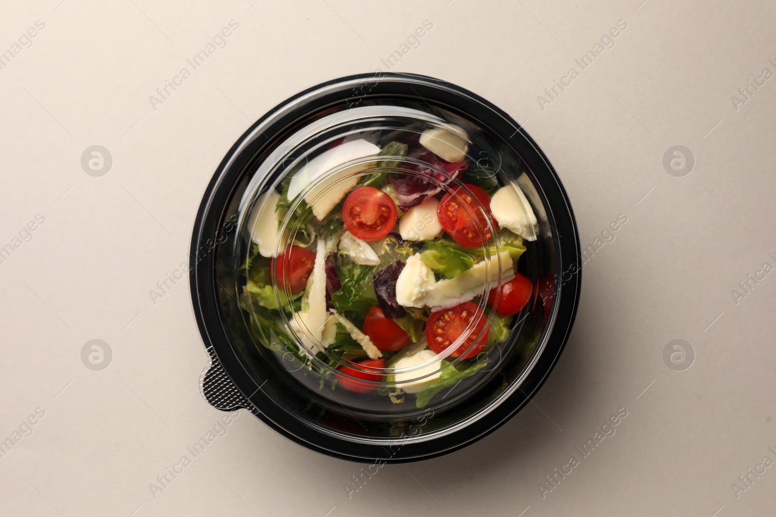 Photo of Tasty food in container on light background, top view