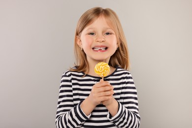 Photo of Portrait of happy girl with lollipop on light grey background