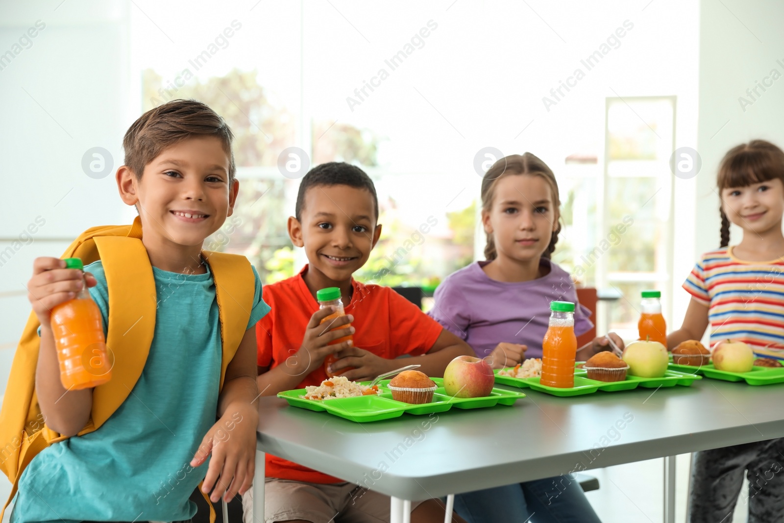 Photo of Children sitting at table and eating healthy food during break at school