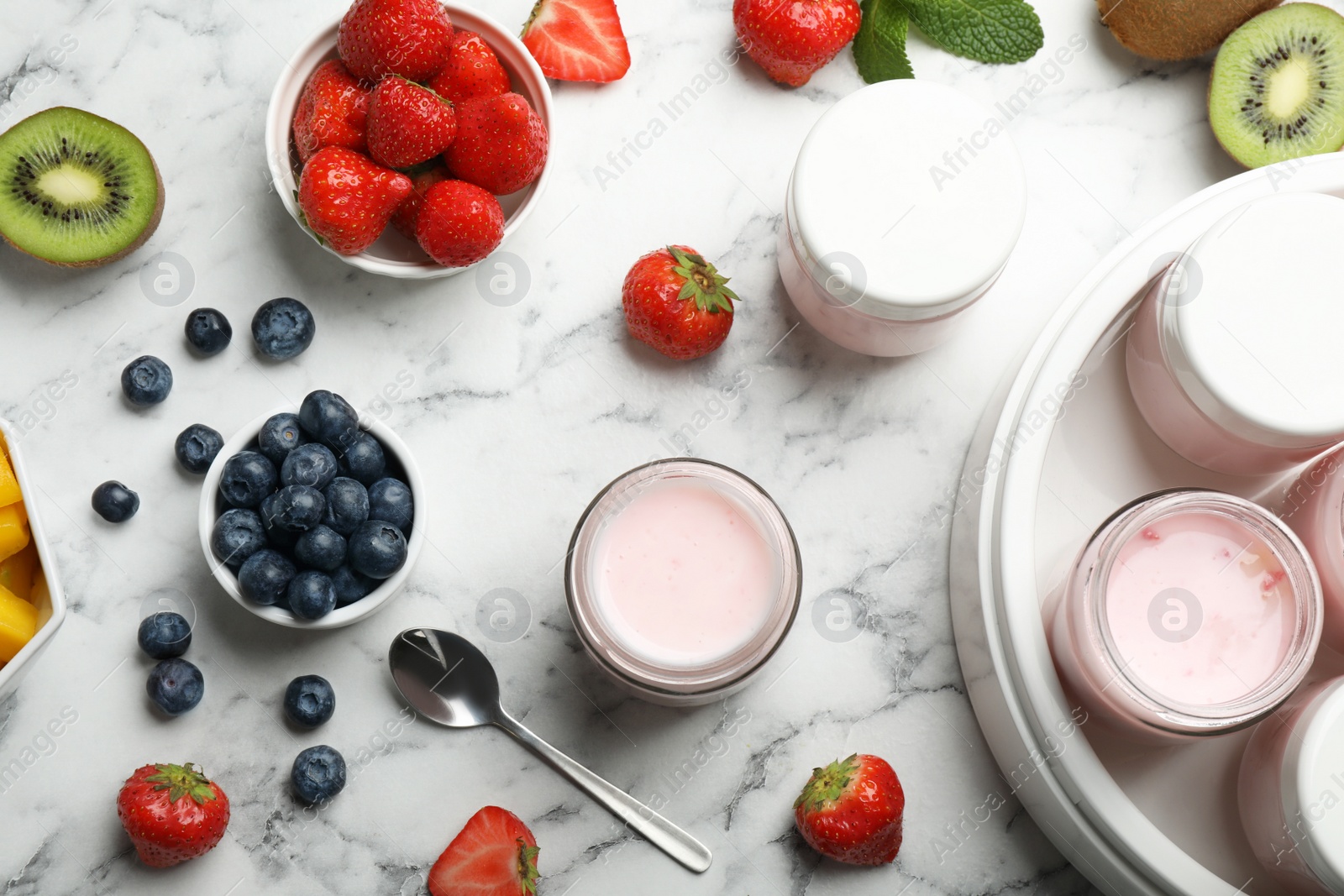 Photo of Modern yogurt maker with full jars and different fruits on white marble table, flat lay