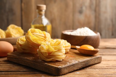 Photo of Uncooked homemade pasta and ingredients on wooden table. Space for text
