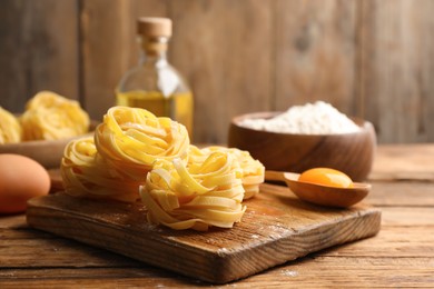 Uncooked homemade pasta and ingredients on wooden table. Space for text