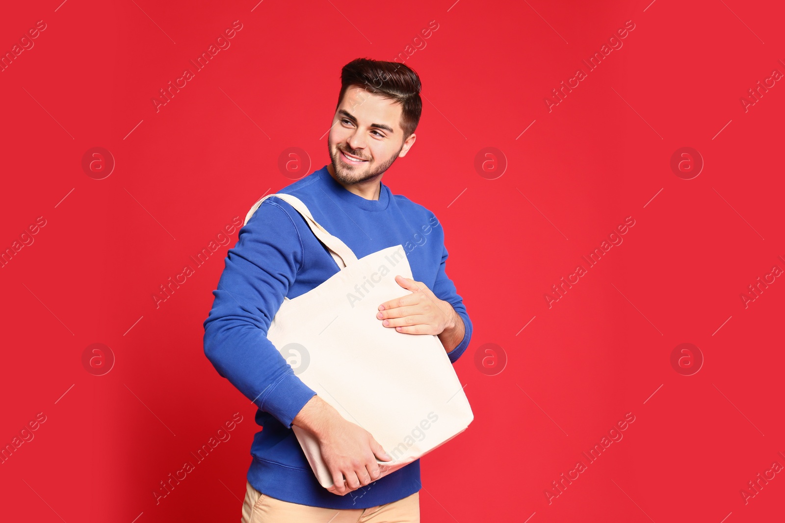 Photo of Portrait of young man with eco bag on red background. Space for text