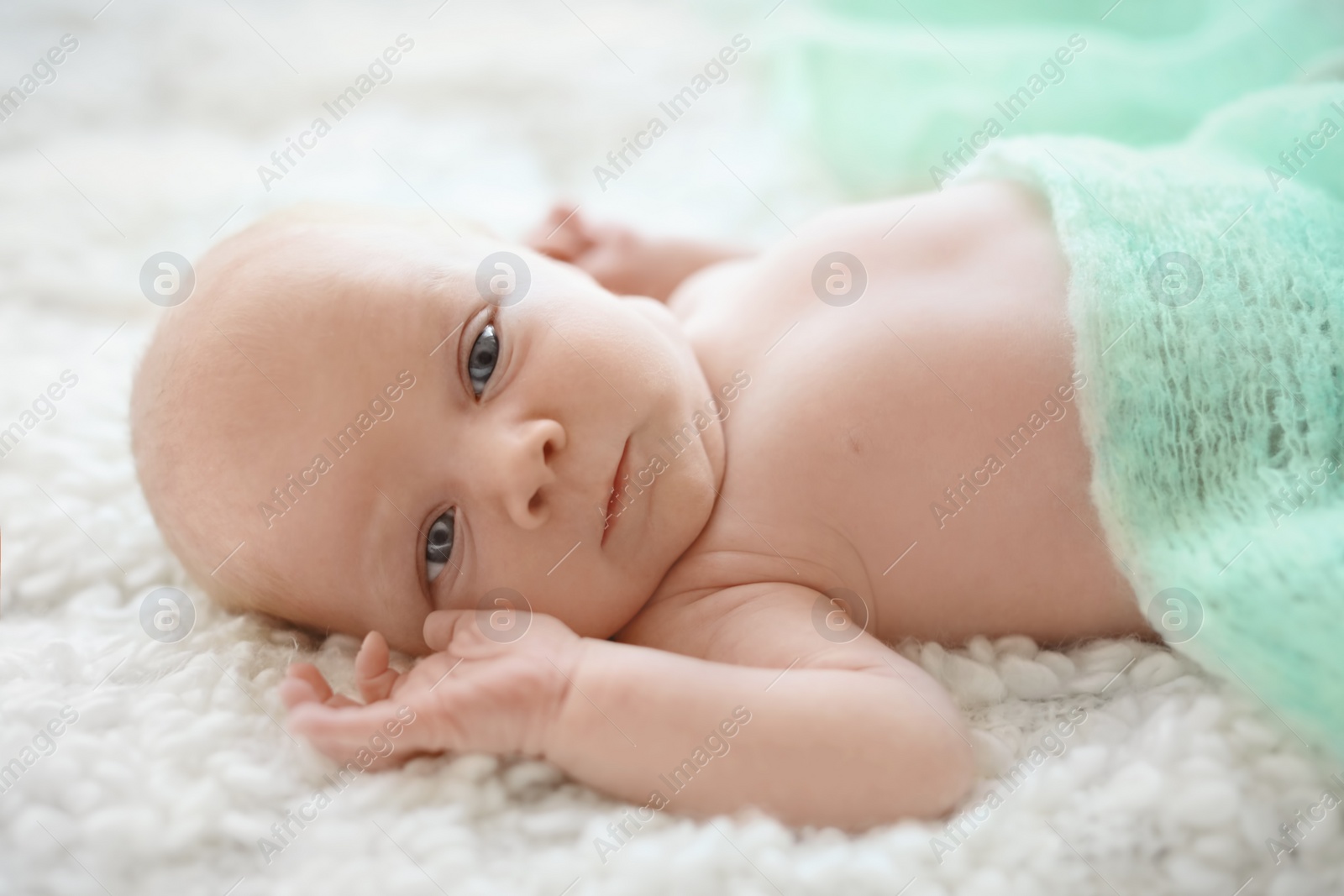 Photo of Adorable newborn baby resting under soft blanket on bed