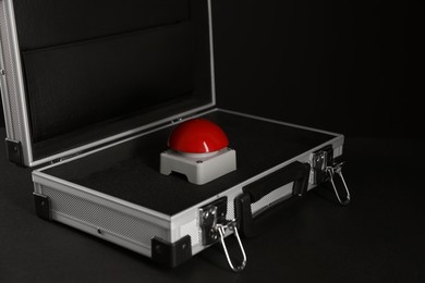 Photo of Red button of nuclear weapon in suitcase on black background. War concept