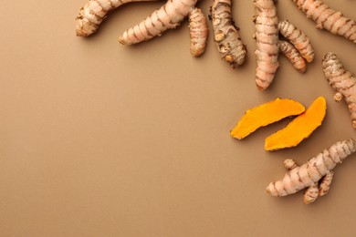 Photo of Many raw turmeric roots on light brown table, flat lay. Space for text