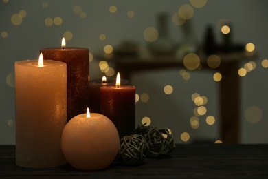 Burning candles on wooden table indoors. Space for text