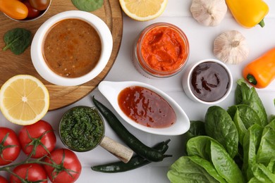 Photo of Different marinades and products on white tiled table, flat lay